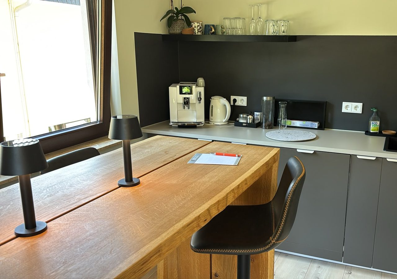 Gemeinschafts-Stehtisch mit Blick in die Küche mit Kaffeemaschine